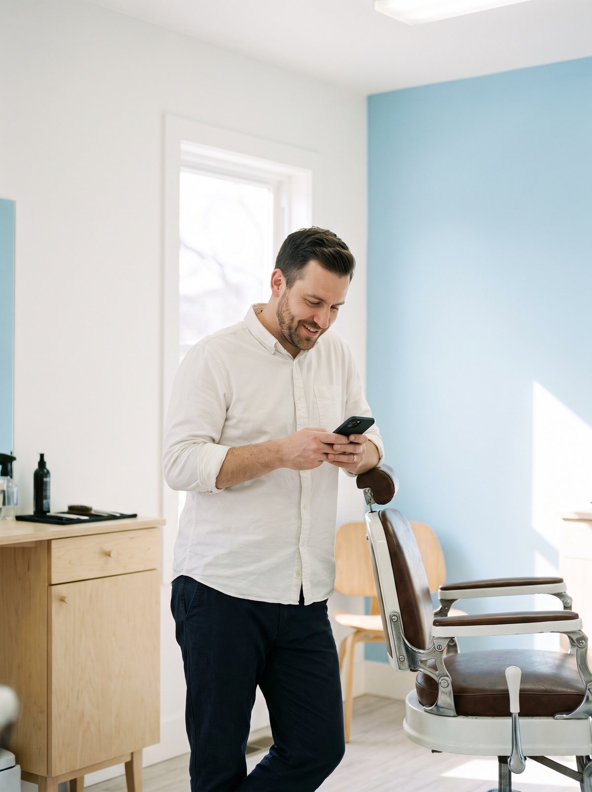 Un barbier consulte son agenda sur son téléphone